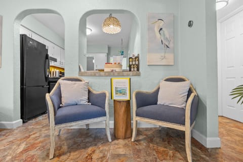 Charming Entryway: Relax in stylish chairs while soaking up beachy vibes and vibrant decor!