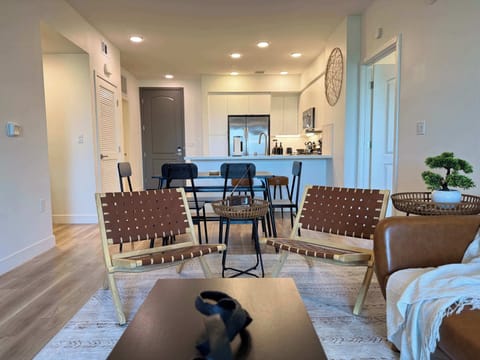 Spacious living room featuring a cozy sofa, two stylish armchairs, a full-size air mattress, and a 65" Smart TV with preloaded access to Netflix, Hulu, and Disney+, all set up for your enjoyment.