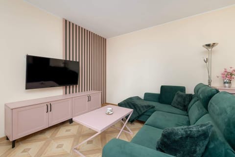 Soft green sofas and subtle pastel decorations create a perfect space to relax with your favorite TV series.