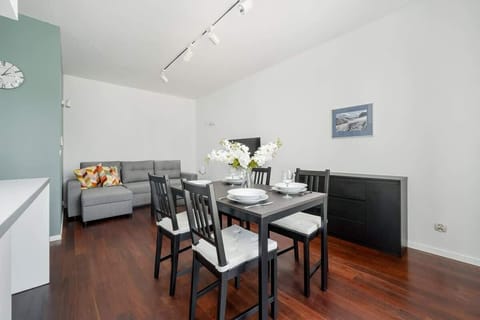 The living area combines an elegant dining table with a comfortable sofa and wall decorations, creating a harmonious space for shared meals and evening relaxation.