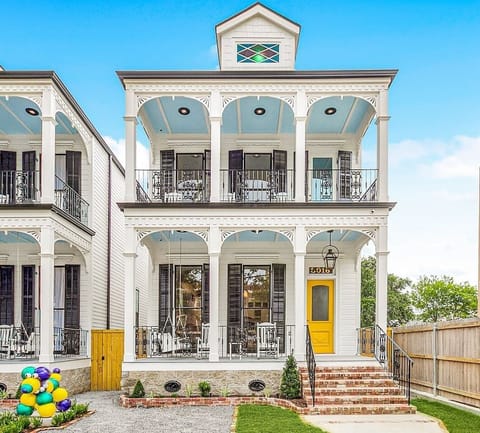 The front view of one of our two 5-bedroom, 5-bath homes on world-famous Canal Street, featuring the iconic "MARDI GRAS BEAD DOG" statue, offers a captivating scene with streetcars passing by.