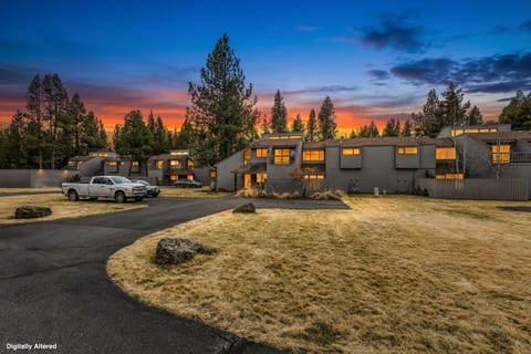 Modern rental property nestled among towering pines under a breathtaking sunset sky, offering serene mountain escape with convenient parking.