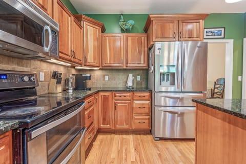 Modern kitchen with stainless steel appliances, granite countertops, and rich wood cabinets.
