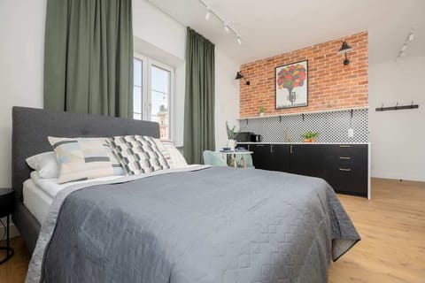 A stylish living room with an exposed brick wall and a kitchenette creates a cohesive, modern space perfect for longer stays.
