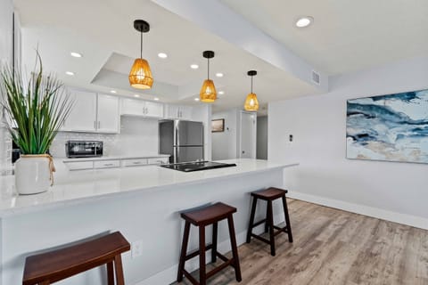 Spacious eat in kitchen area with bar seating, modern lighting, and a bright open layout for gathering.