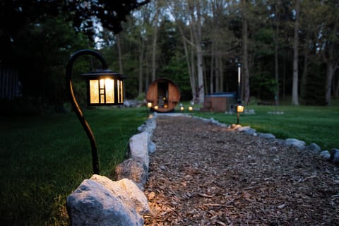 Lit garden path leading to a private sauna and hot tub retreat