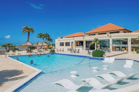 The Gold Coast resort swimming pool, one of three complete pools. Take a refreshing swim with shallow lounging areas, comfortable sun chairs, and plenty of space to relax under the Aruba sun.