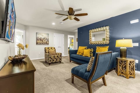 Relax in the stylish living room with plush navy seating, gold accent pillows, and a large TV for group entertainment.