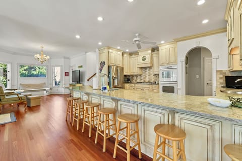 Spacious white kitchen with over-sized counter with overflow seating for 8. 