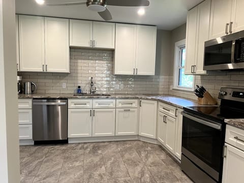 Fully equipped kitchen with all essential needs including coffee pot, grinder, pots, pans, baking sheets, blender, toaster, plastic and glass drink ware and plates, and more.