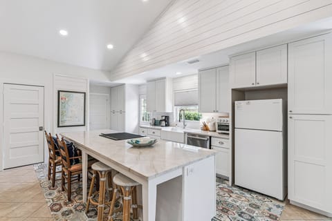 Cook meals together in this bright kitchen with marble countertops, modern appliances, and a spacious island perfect for gathering.