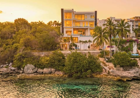 Evolve Isla at golden hour. A 9 bedroom architectural villa perched above a cove, uninterrupted sunset views and Caribbean blue water at your doorstep