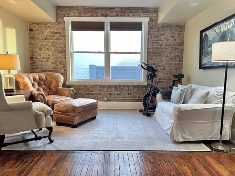 Sitting area of living room with leather chair/ottoman and winged back chair. 