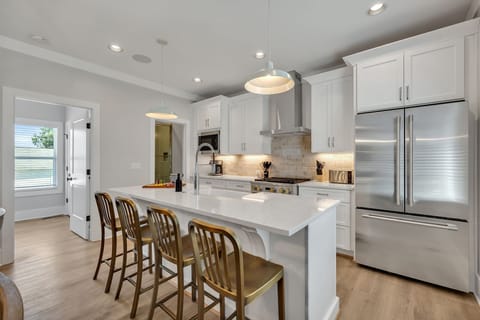 2nd Floor: Fully equipped kitchen stocked with all culinary essentials featuring stainless-steel appliances and a kitchen island offering ample counter space and bar seating.