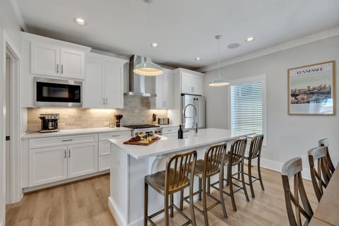 2nd Floor: Fully equipped kitchen stocked with all culinary essentials featuring stainless-steel appliances and a kitchen island offering ample counter space and bar seating.