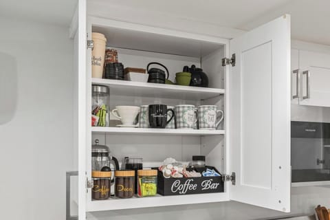 - Fully stocked coffee bar with mugs and brewing tools  
- Organized cabinet with French press and pour over gear  
- Thoughtful setup for coffee lovers during their stay  