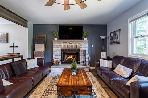 Warm and inviting living room with a brick fireplace, cozy leather seating, and stylish rustic accents.
