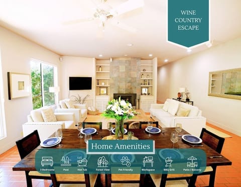 Spacious living/dining area with stone fireplace, white sofas, and a wood dining table set for entertaining. Amenities include 3 bedrooms, a pool, a hot tub, forest views, a pet-friendly policy, a workspace, a BBQ grill, and patio/balcony access