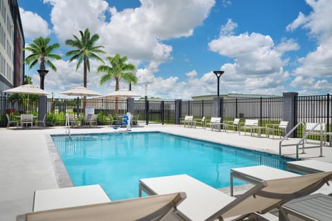 Dive into sunny poolside relaxation with loungers and palms.