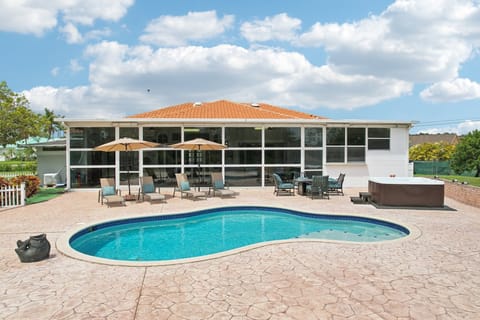 Pool area with a private swimming pool, hot tub,  lounge chairs, and umbrellas.