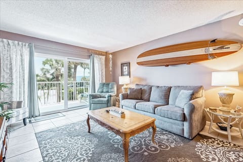 Spacious living room with a cozy sofa, TV, and surf-inspired decor