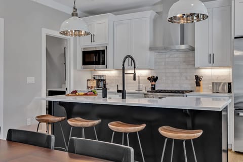 Unit 1 - 2nd Floor: Fully equipped kitchen, complete with all essential culinary tools, boasts stainless-steel appliances and a spacious island with ample counter space and bar seating.