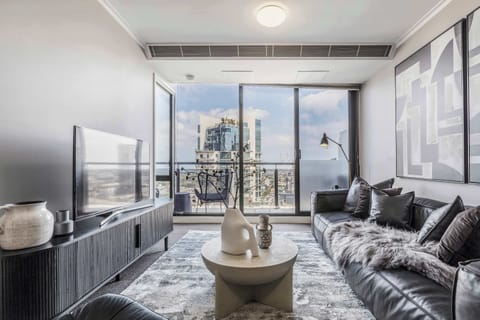 LIVING ROOM: A sleek sanctuary of black-and-white contrasts, where plush seating invites quiet relaxation beside floor-to-ceiling windows capturing the city’s endless rhythm.