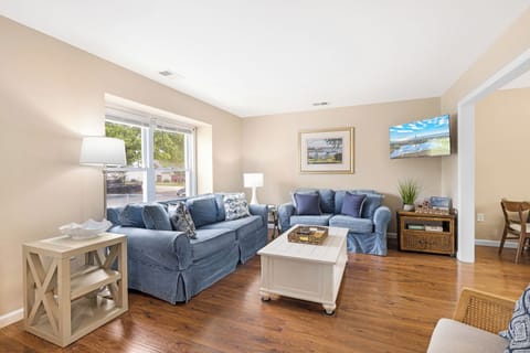 Living room with comfortable seating, TV, books, and opens to the kitchen