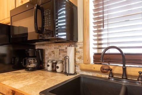 Double sink surrounded with hickory cabinets, luxurious tilework, and wood framed window.