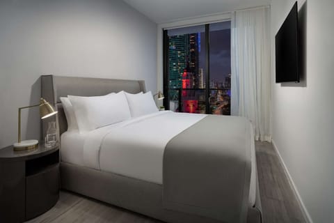 Unwind in crisp linens with sparkling city lights outside.