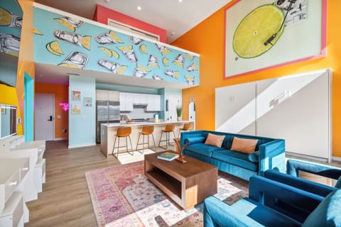 Bright open-concept living space with a Smart TV, queen Murphy beds, and a modern kitchen with bar seating—plus a private balcony right off the room for fresh air + skyline vibes!