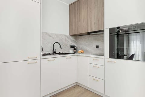 A minimalist kitchen corner with sleek white cabinetry and black appliances.

