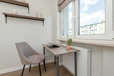 A small workspace in the bedroom, with a desk, chair, and floating shelves by the window.

