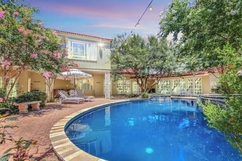 Bask in the sunshine in this glamorous outdoor oasis with a sparkling Art Deco-inspired black pool, lush greenery, and stylish loungers for relaxation.