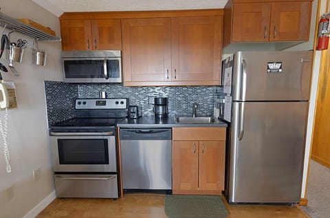 The modern kitchen has stainless steel appliances and a backsplash.