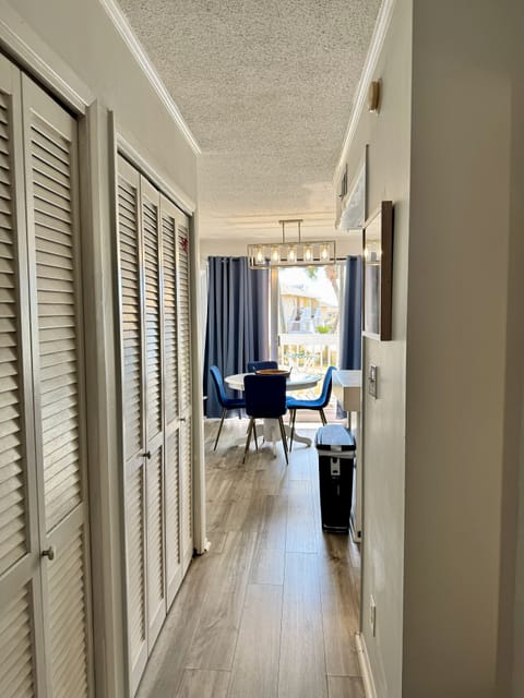 Your private hallway leads to the bright dining area where vibrant blue chairs invite memorable meals with natural light streaming in.