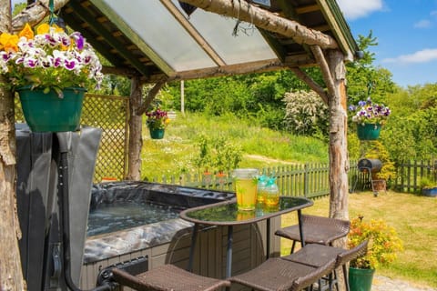 Hot tub under rustic shelter with views over the garden and flower meadow