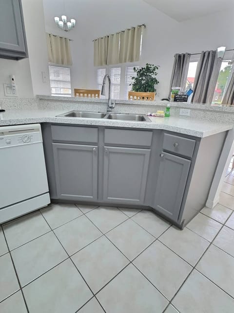 This bright kitchen features sleek gray cabinetry and a pristine white countertop, creating an inviting workspace filled with natural light. The spacious layout makes meal preparations easy and enjoyable for every guest.