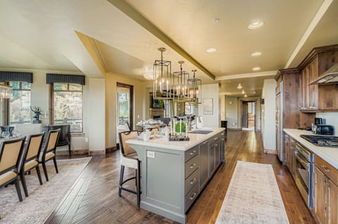 This chef-inspired kitchen boasts warm wood cabinetry, a large marble island with seating for four, and elegant lantern pendant lights. Perfect for hosting, the open layout is both stylish and functional.