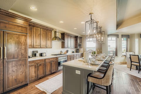 This chef-inspired kitchen boasts warm wood cabinetry, a large marble island with seating for four, and elegant lantern pendant lights. Perfect for hosting, the open layout is both stylish and functional.