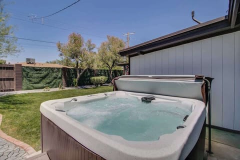 Sink into the bubbling hot tub overlooking the green yard—an easy place to unwind under open blue skies, with the house just steps away.