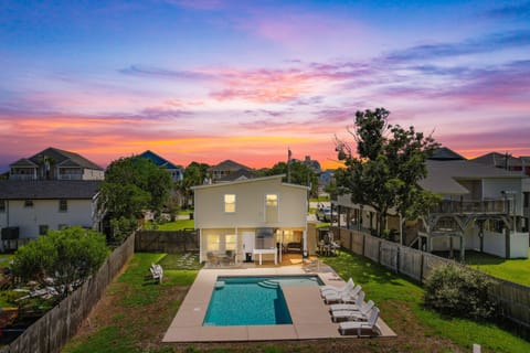 Stunning sunset paints the sky above this coastal rental home featuring a private swimming pool and spacious backyard.