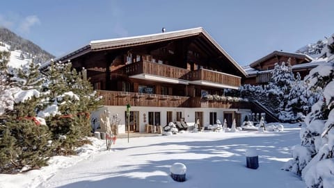 The beautiful chalet, surrounded by snow, glistens under the warm sun on a winter day.