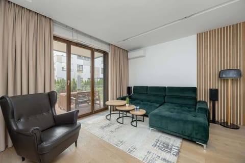 A spacious living room with a large window, green sofa, and elegant coffee table encourages relaxation and gatherings.