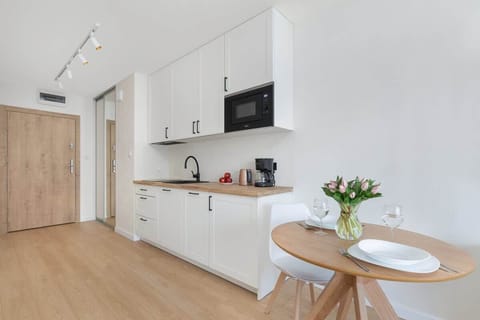 Open kitchenette with elegant white cabinets, modern appliances, and space for meal preparation.