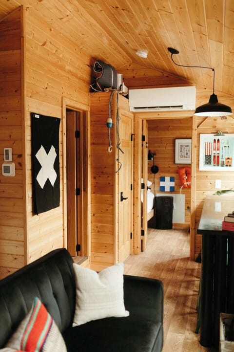Open concept living room, kitchen and dining room make this tiny cabin feel light and airy. Large picture windows provide gorgeous forested views from the privacy of your cabin in any season!