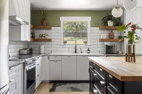 Modern kitchen with electric range, farmhouse sink, and open shelving
