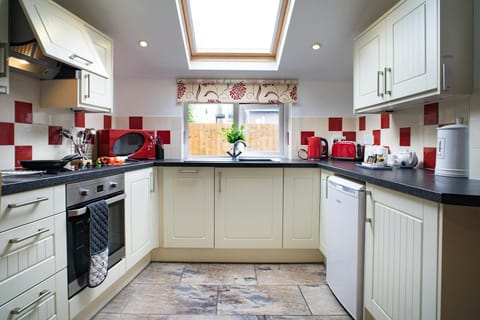 Kitchen with window and skylight: oven and hob, fridge, microwave, kettle and toaster