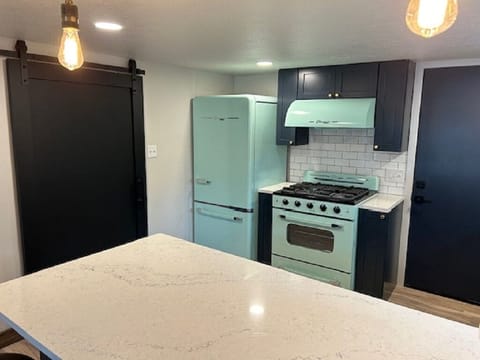 Fridge and stove, sliding barn door to washer/dryer and bathroom area.