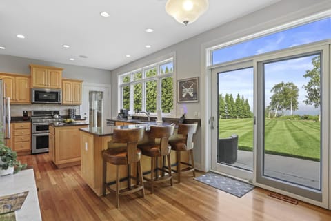 Fully stocked kitchen with island barstool seating, walkout access to the patio and porch, and luxury appliances.